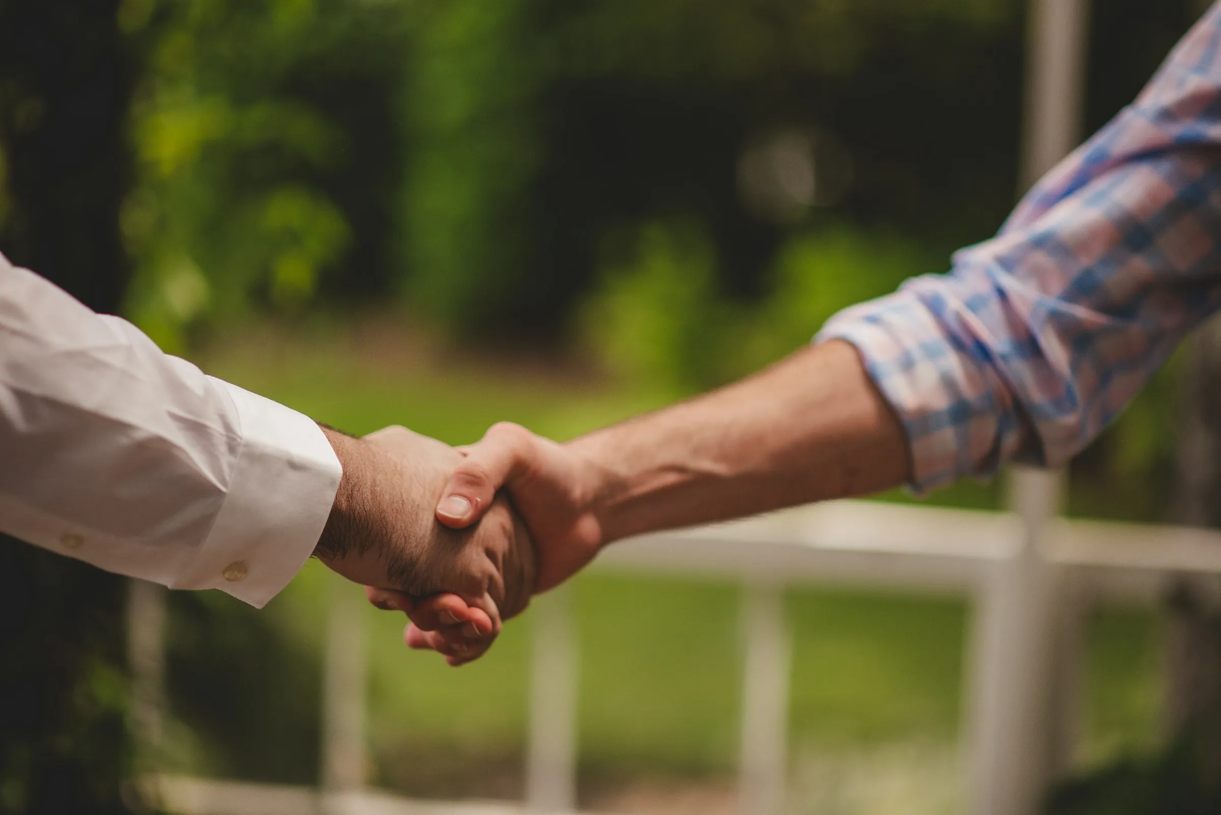 Two people shaking hands outdoors to close a deal